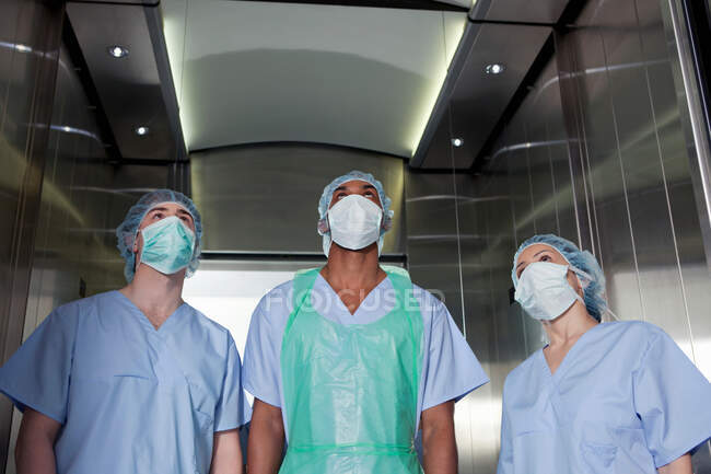 Tres cirujanos en ascensor del hospital - foto de stock