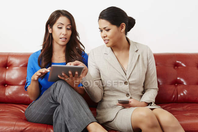 Dos empresarias teniendo reunión, mirando tableta digital - foto de stock