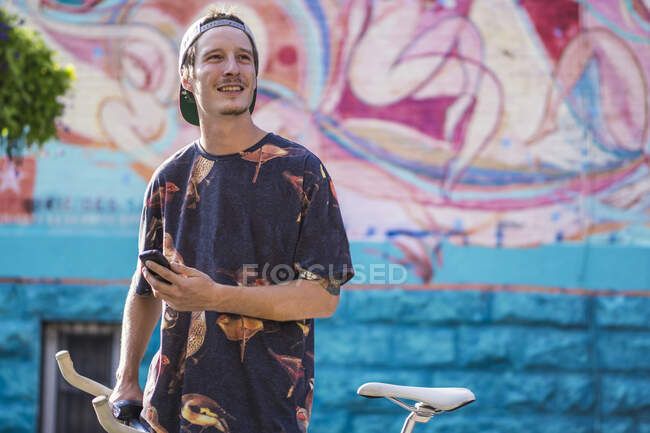 Young man smiling against graffiti wall, Le Plateau, Montreal, Quebec, Canada — Stock Photo