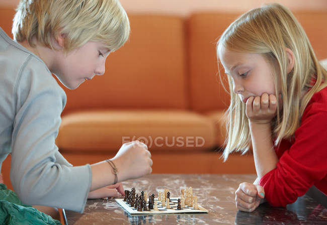 Niños jugando ajedrez en la sala de estar - foto de stock