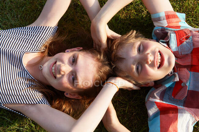Enfants couchés dans l'herbe ensemble — Photo de stock