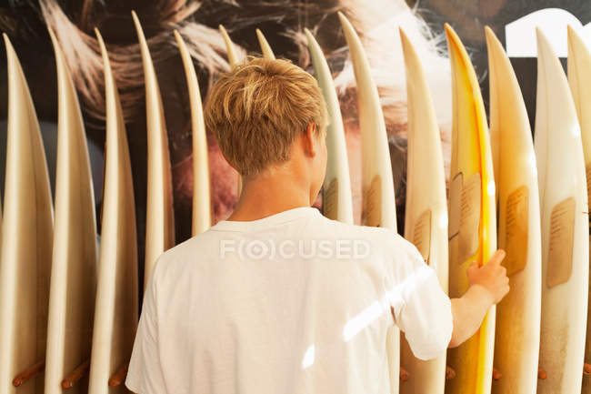 Молодой человек смотрит на доски для серфинга — стоковое фото