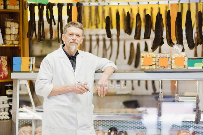 Carniceiro em pé no balcão de carne — Fotografia de Stock
