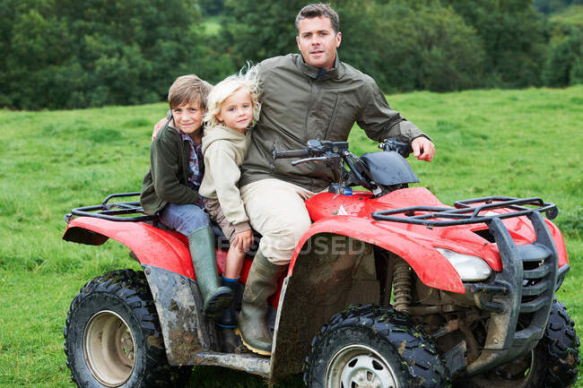 Отец и дети на квадроцикле — стоковое фото