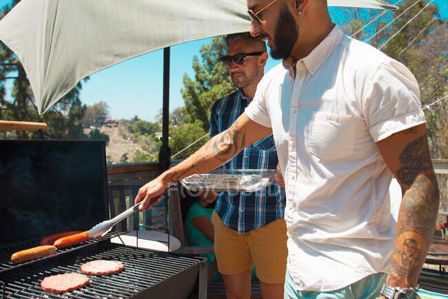 Two mid adult brothers barbecuing in garden — Stock Photo