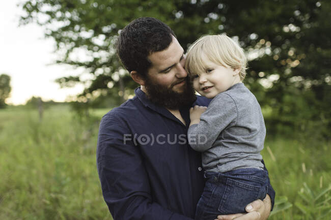 Pai segurando jovem filho no campo — Fotografia de Stock