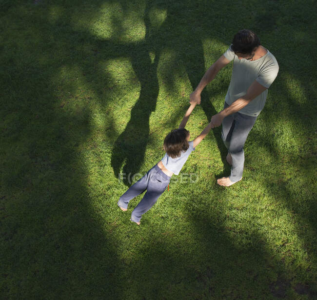 Отец размахивает сыном вокруг, на улице, возвышенный вид — стоковое фото