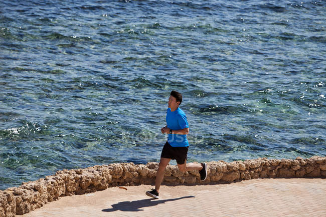 Hombre corriendo en la costa pavimentada - foto de stock