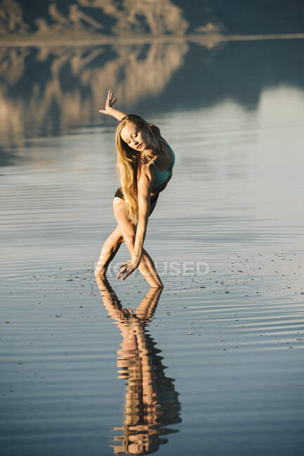 Female ballet dancer poised bending forward in lake, Bonneville Salt Flats, Utah, USA — Stock Photo