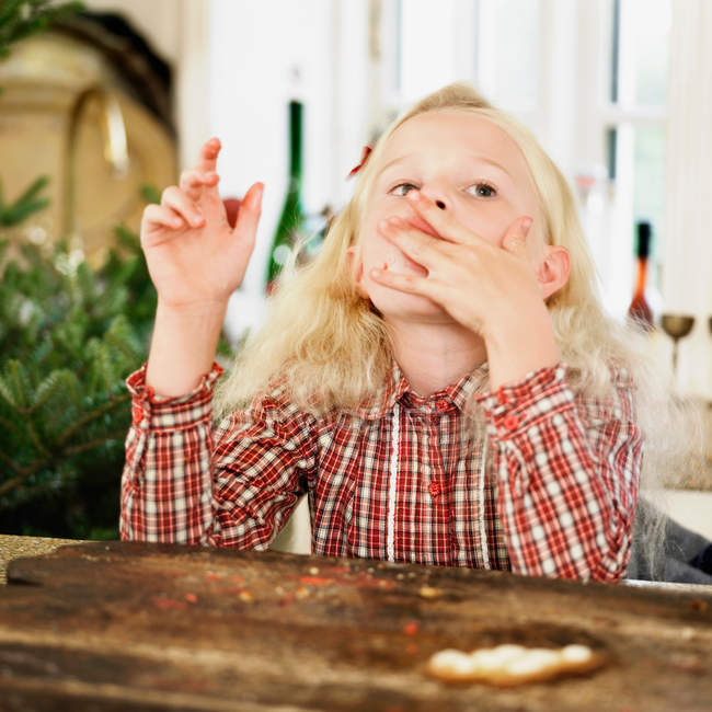 Girl eating Christmas cookies in kitchen — Stock Photo