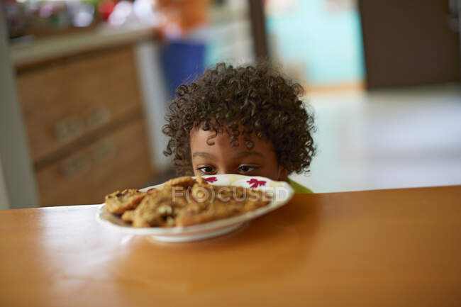 Хлопчик дивиться на тарілку печива — стокове фото