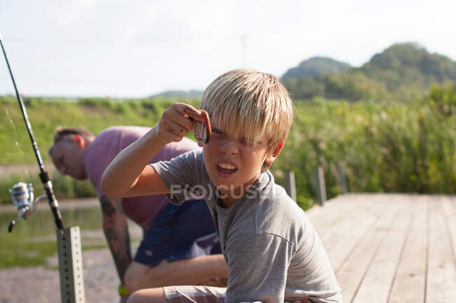 Padre e hijo pescando, niño sosteniendo gusano - foto de stock