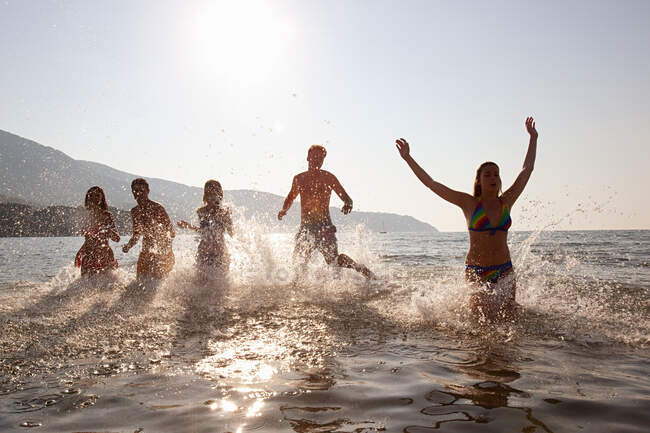 Jovens amigos saltando no mar — Fotografia de Stock