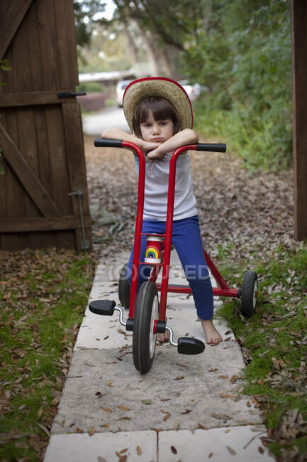 Porträt eines vierjährigen Mädchens, das auf seinem Dreirad im Garten sitzt — Stockfoto