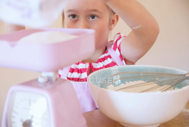 Дівчина зважує інгредієнти на кухні — стокове фото