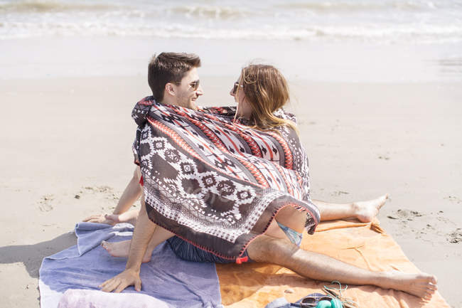 Casal contemporâneo ter um bom tempo na praia sob cobertores de praia — Fotografia de Stock