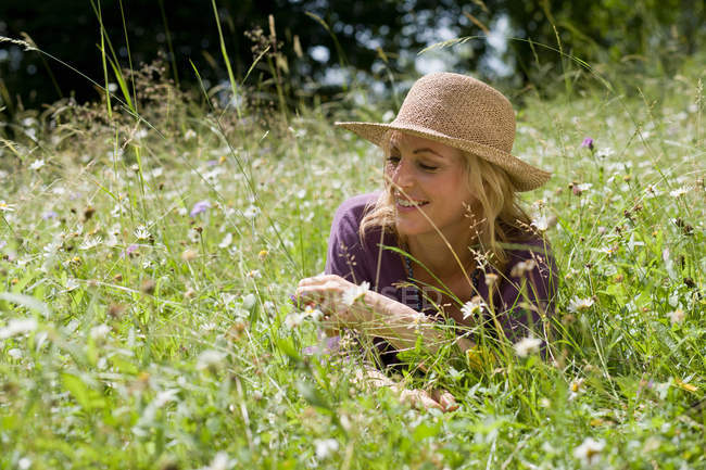 Усміхнена жінка сидить на полі пшениці — стокове фото