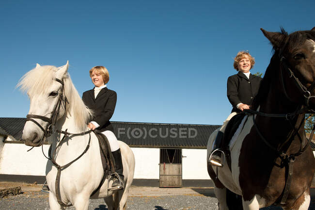 Dos chicos montando caballos - foto de stock