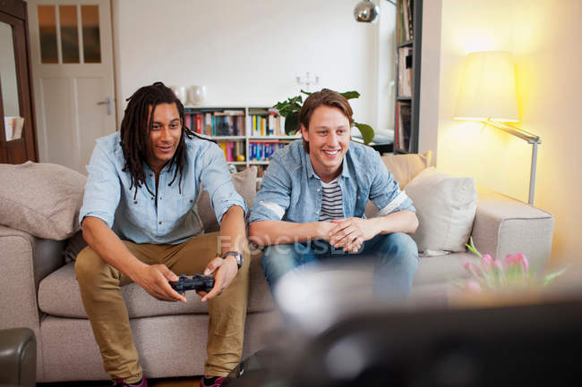 Hommes jouant à des jeux vidéo dans le salon — Photo de stock