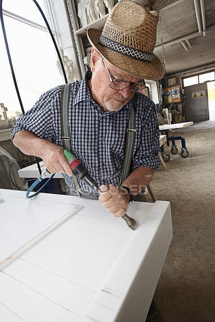 Worker chiseling slab of stone — Stock Photo