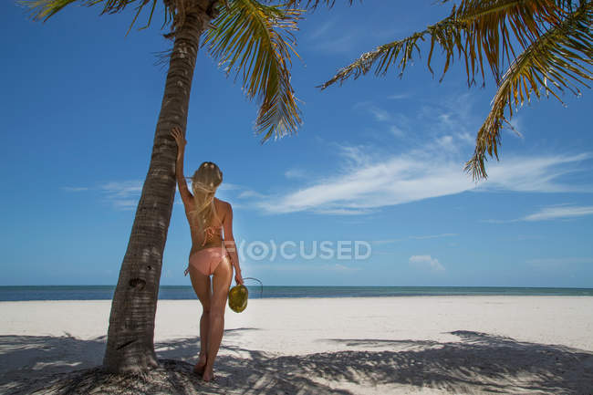 Woman holding tropical fruit on beach — Stock Photo