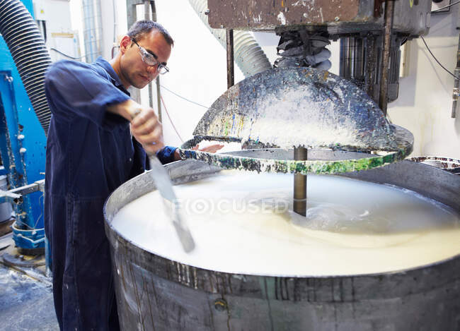 Arbeiter rührt Bottich mit Flüssigkeit in Fabrik um — Stockfoto