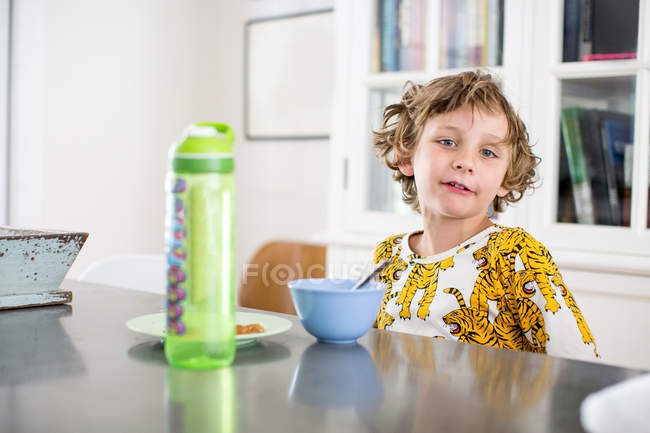 Портрет мальчика завтракающего за кухонным столом — стоковое фото