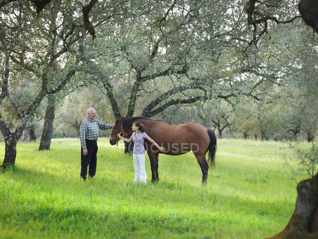 Nonno e nipote accarezzando cavallo — Foto stock