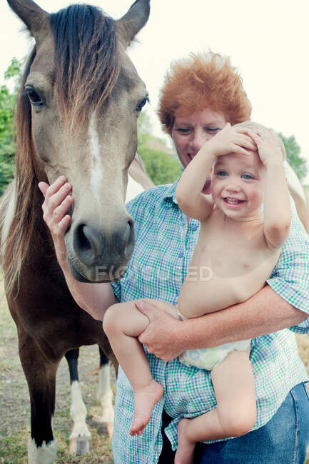 Grand-mère et tout-petit avec poney — Photo de stock