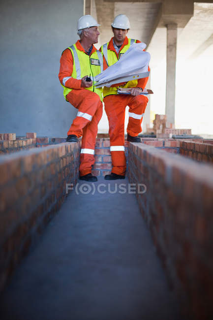 Arbeiter lesen Baupläne vor Ort — Stockfoto