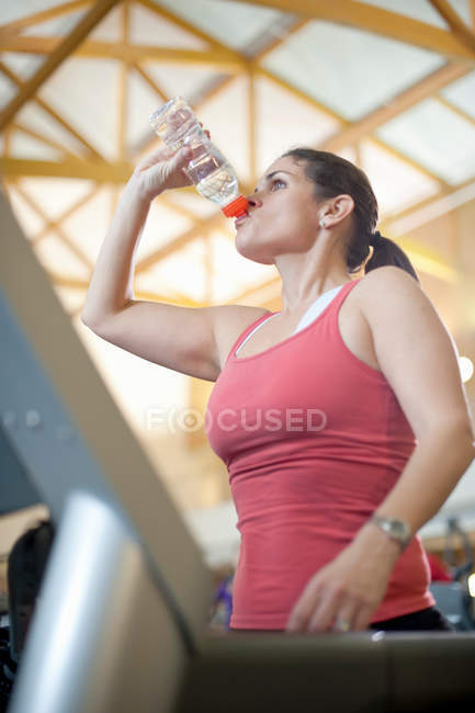 Жінка п'є пляшку води в спортзалі — стокове фото