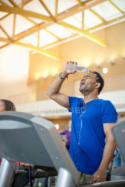 Человек поливает себя водой в спортзале — стоковое фото