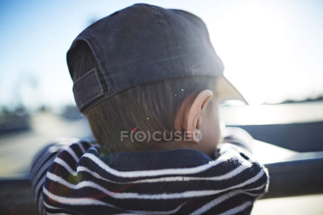 Вид ззаду хлопчика з шапочкою, що спирається на перила — стокове фото