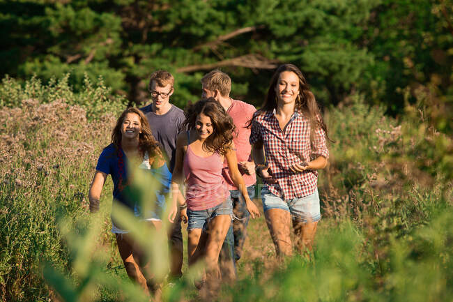 Five friends walking through field — Stock Photo