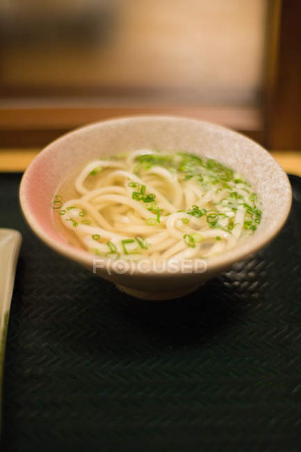 Tagliatelle udon in ciotola con erbe servite sul tavolo — Foto stock
