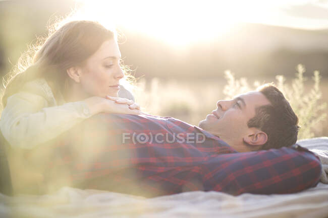 Young couple lying outdoors on blanket relaxing — Stock Photo