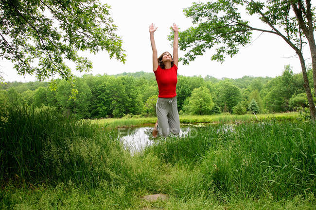 Donna che salta vicino al lago rurale — Foto stock