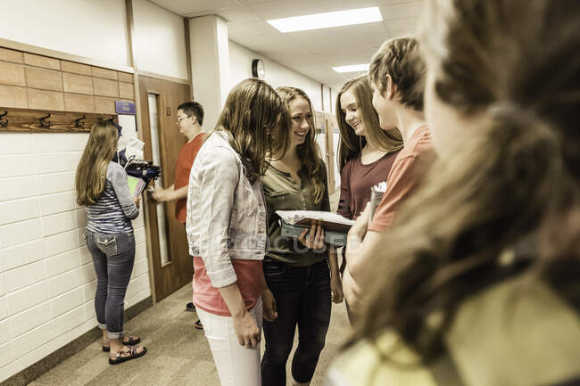 Adolescentes mirando el cuaderno en el pasillo de la escuela secundaria - foto de stock