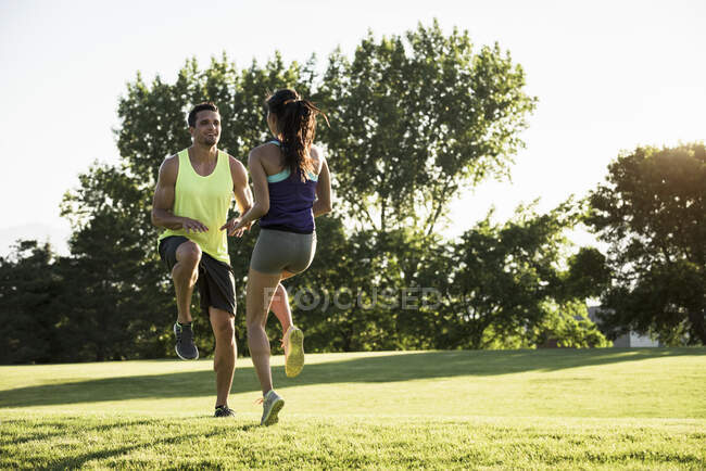 Young man and woman doing running on spot training in park — Stock Photo
