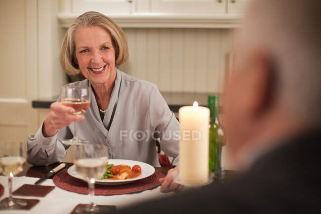 Старшая женщина с вином за ужином — стоковое фото