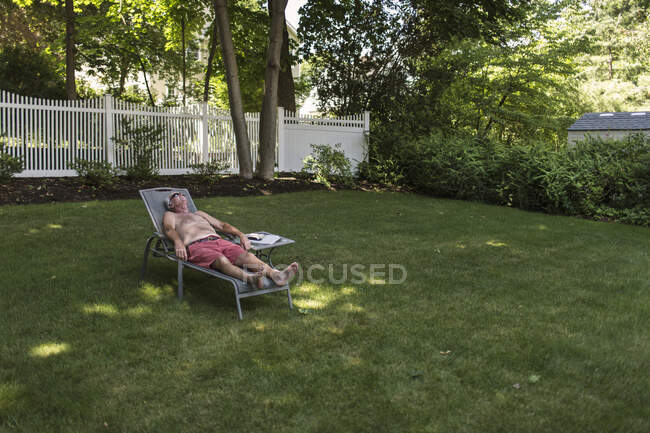 Hombre mayor tomar el sol y relajarse en su patio trasero - foto de stock