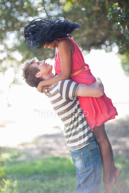 Homem levantando namorada ao ar livre — Fotografia de Stock