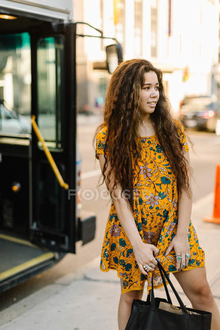 Young woman standing on city street and holding bag — Stock Photo