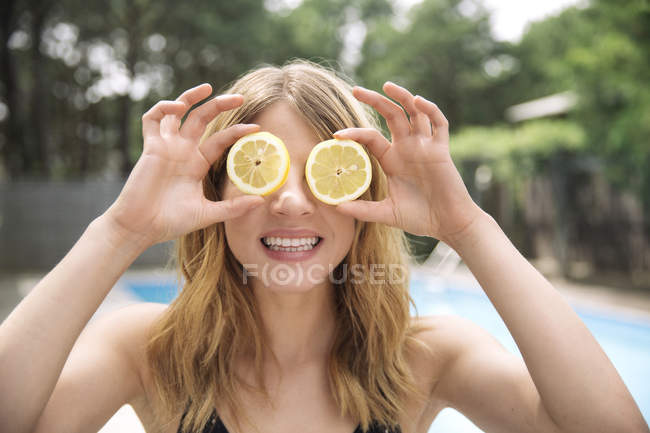 Retrato de mujer cubriendo ojos con rodajas de limón, Amagansett, Nueva York, EE.UU. - foto de stock