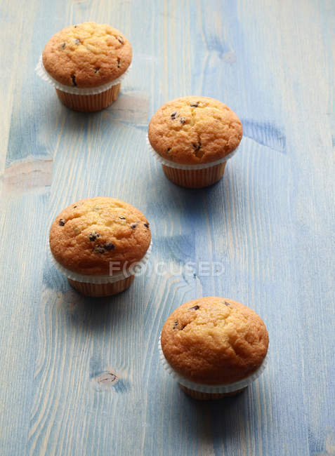 Vier Muffins auf blauem Holztisch — Stockfoto