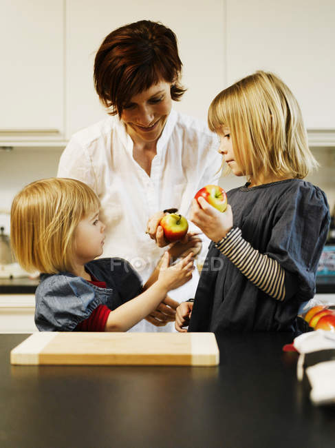 Mother and daughters eating in kitchen — Stock Photo