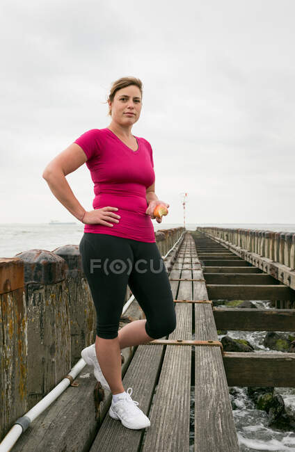 Frau steht mit Sportkleidung auf Seebrücke — Stockfoto