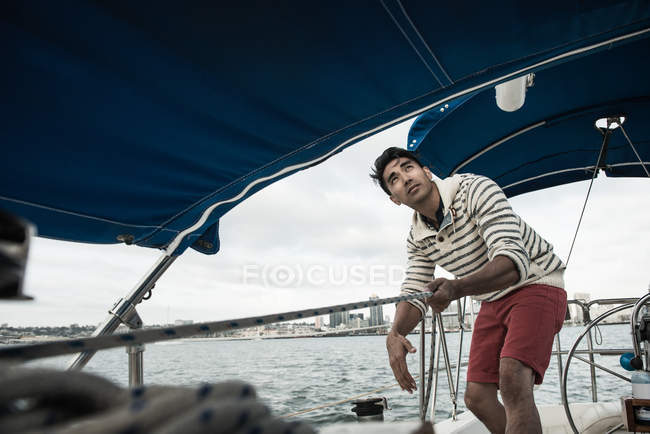 Young man looking up on sailing boat — Stock Photo