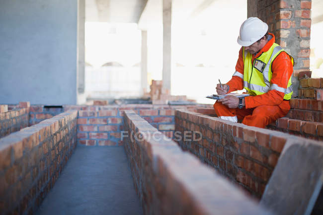 Worker writing on clipboard on site — Stock Photo