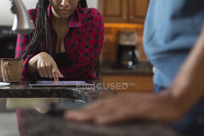 Couple adulte moyen utilisant une tablette numérique au comptoir de la cuisine — Photo de stock